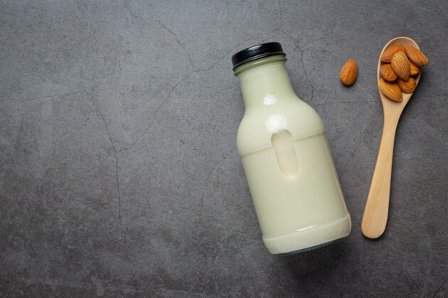 新鲜杏仁牛奶在瓶子里 杏仁在深色的背景上木头棕色奶制品