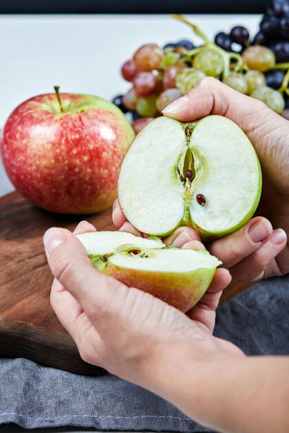 新鲜把苹果切成两半 在木板上放一串葡萄葡萄收获木材