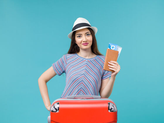 旅行前景度假的女人拿着她的红包拿着蓝色背景的票旅行度假的女人成人持有微笑