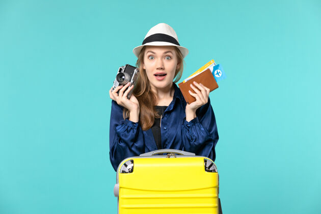 人前视图年轻女子手持相机和机票在蓝色背景海上旅行飞机航行年轻女子票旅行