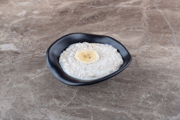 有机成熟的香蕉片放在一碗粥上 放在大理石表面风味健康香蕉