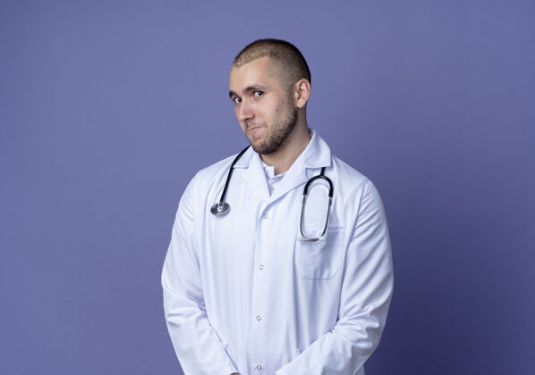 医生体贴的年轻男医生穿着医用长袍和听诊器看着隔离在紫色墙上的前墙医学穿着人