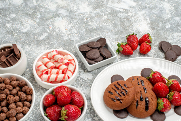 盘子底部特写饼干草莓和圆形巧克力放在椭圆形的盘子里 糖果草莓巧克力麦片放在灰白色的桌子上浆果蓝莓餐桌