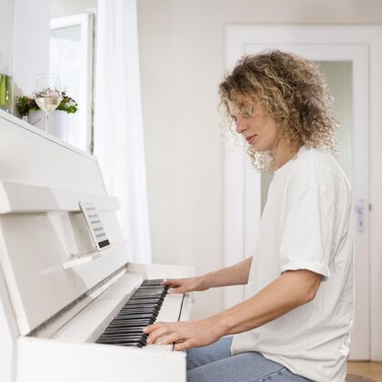 放松一个金发女人弹钢琴的侧视图侧视广场音乐家