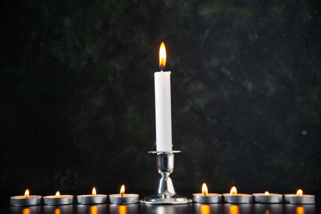 黑燃烧的蜡烛作为一个在黑色的表面下降记忆的正面视图记忆蜡烛葬礼
