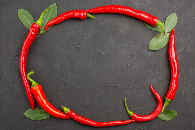 烹饪顶视图红色辣椒圈和支付在黑色表面上的叶子辣椒辣椒健康