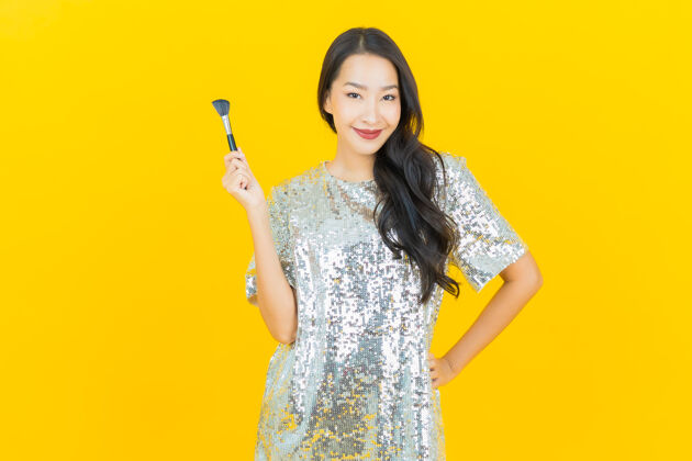 护理肖像美丽的亚洲年轻女子化妆刷化妆品上的黄色网络影响者化妆