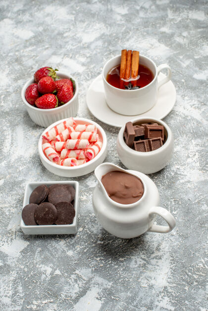 八角灰白色的桌子上放着可可糖果草莓巧克力茶肉桂和八角茴香籽的底视图碗种子茶碟餐