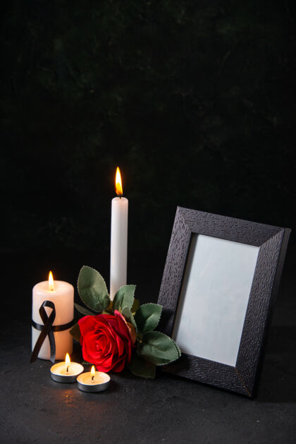 蜡烛前视图燃烧蜡烛与相框和花在黑暗的表面火焰黑暗燃烧的蜡烛