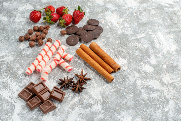 木头底视图草莓巧克力糖果谷类食品肉桂茴香种子在灰白色桌子的左侧有自由空间底部壁板香料