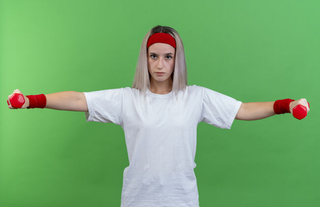 背带自信的年轻白人运动女孩戴着背带和头带开放腕带保持