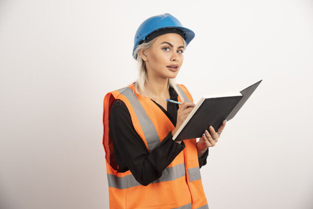 职业女建筑工人在笔记本上写字高质量的照片头盔钢笔女性