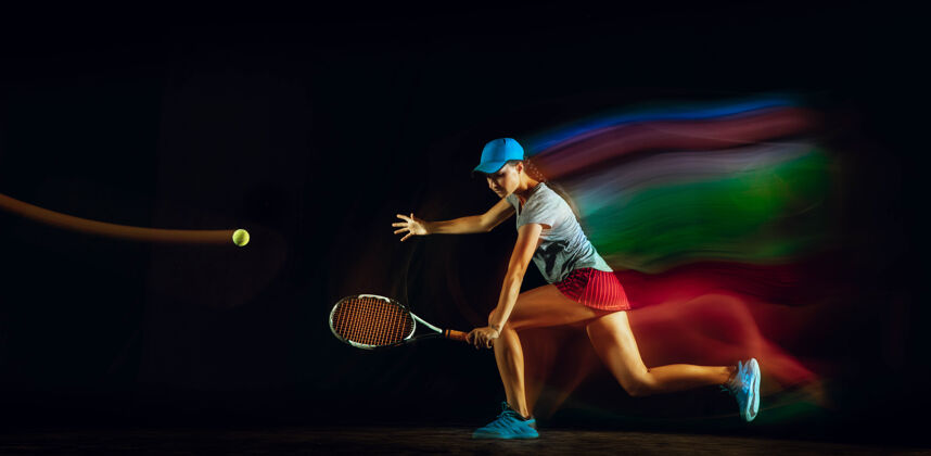 明亮一个打网球的女人孤零零地站在黑色的墙壁上 混合着柔和的光线室内运动球拍