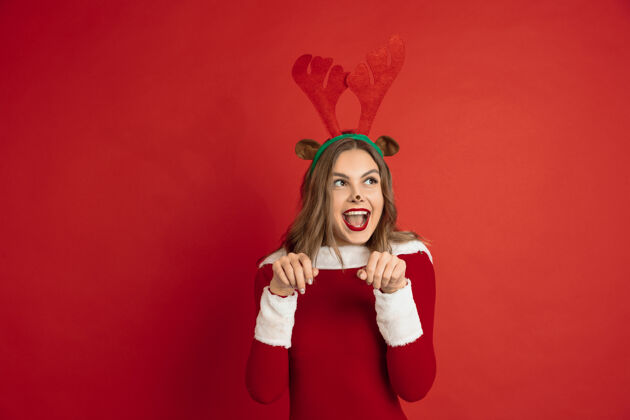 情绪美丽的女人像圣诞鹿隔离在红色的表面概念新年寒假心情幽默女性快乐