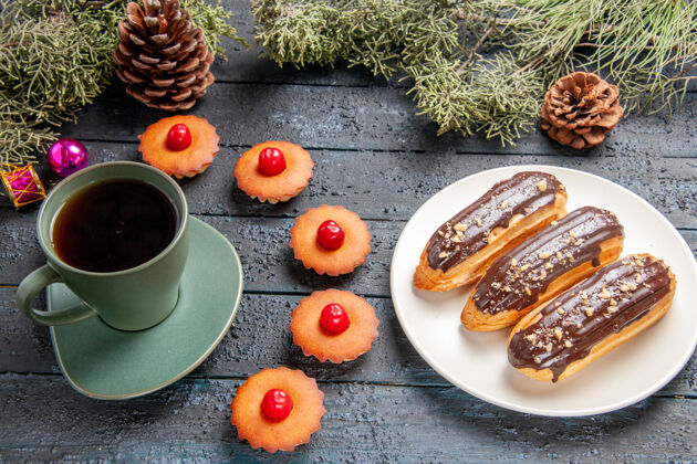 食物下图：白色椭圆形平板杉树树枝上的巧克力蛋糕 圣诞玩具 纸杯蛋糕 深色木质地面上的一杯茶底部深色咖啡