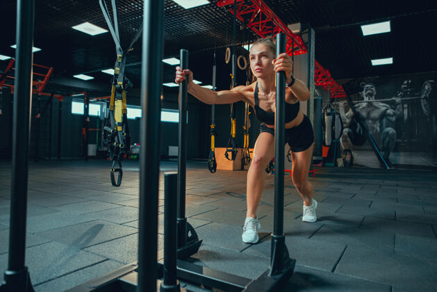运动员年轻肌肉发达的女人在健身房练习形状健美训练