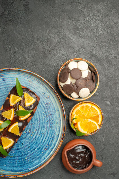 美味蛋糕黑桌子上装饰着柠檬和巧克力的美味蛋糕和其他饼干的垂直视图罐头桶蜡笔