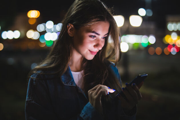 女性年轻女孩用数码平板电脑上的夜美灯在城市波基灯光女人空白