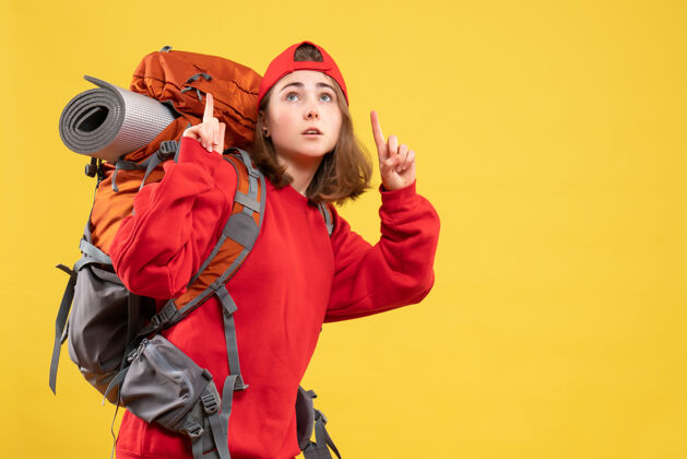 背包正面图：穿着红色背包的年轻女旅行者手指向上手指帽子前面