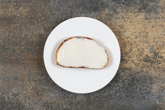 涂抹在白色盘子上放一片带酸奶油的烤面包片正餐美味小吃
