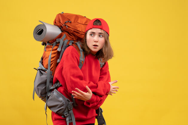 前面正面是年轻的女旅行者 背着红色的背包帽子成人背包