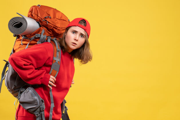 活跃正面图红色背包的年轻女子站在黄色的墙上前面年轻女子背包