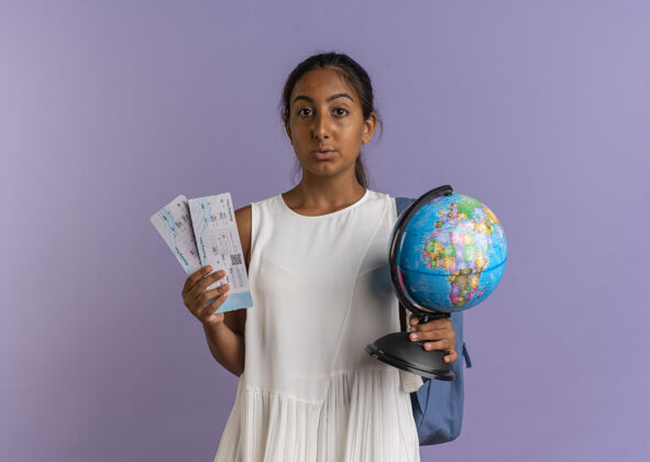 地球仪看着镜头 年轻的女学生背着包拿着地球仪和紫色背景的门票女学生背紫色