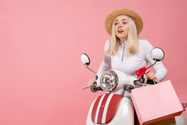 快乐前视图骑着轻便摩托车的年轻女士拿着购物袋和购物卡年轻女士购物设备