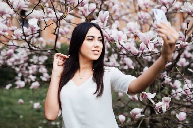 樱花美丽时尚的白种女人在花木兰花园自拍俯瞰图成人年轻美丽