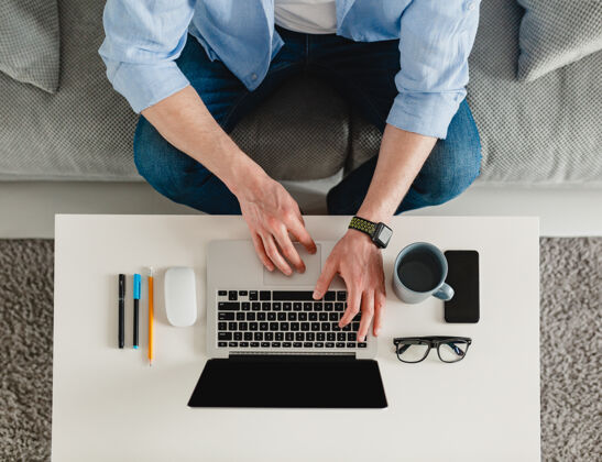 手机桌子工作场所特写男人手在家工作在笔记本电脑上打字科技铅笔鼠标