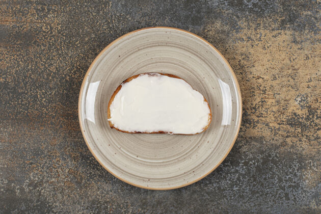 奶制品在陶瓷盘子上放一片烤面包和酸奶油酸奶油小吃涂抹