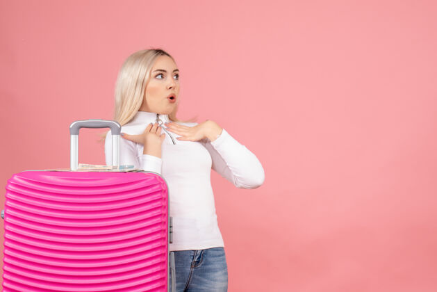 成人前视图：一个穿着粉色手提箱的漂亮女人在看什么东西时尚正面女士