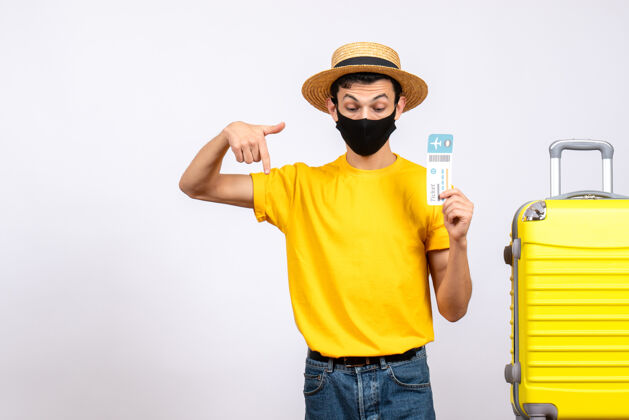 票正面图：戴着草帽和面具的年轻人站在黄色手提箱旁 手里拿着旅行票 指着下面黄色人男人