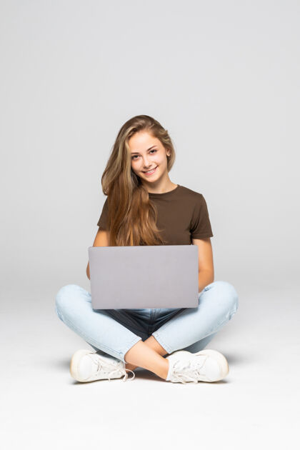 电脑年轻随意的女人坐下来微笑着拿着笔记本电脑隔离在白墙上笔记本电脑成人空间