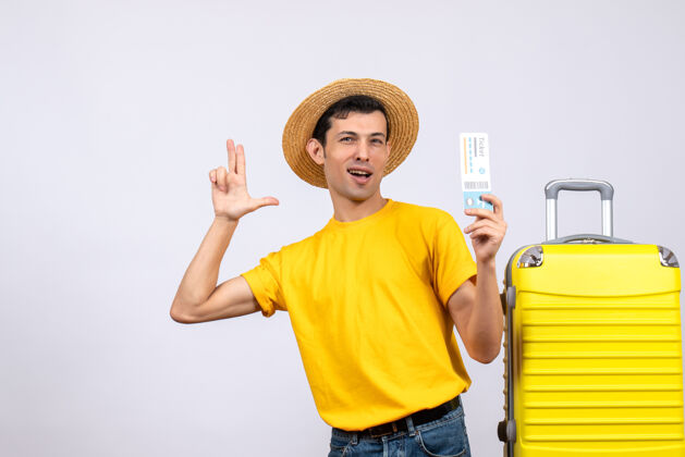 票正面图年轻游客站在黄色手提箱旁拿着手持枪做票手指枪帽子