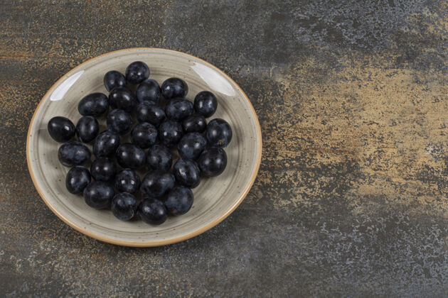 有机新鲜的黑葡萄放在陶瓷盘子里浆果可口食品