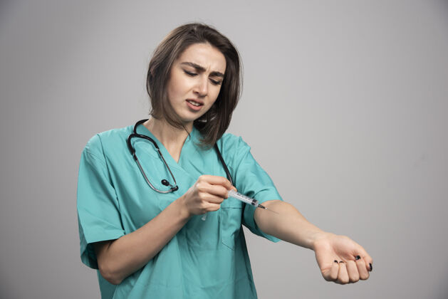 健康穿着制服的年轻医生用注射器给自己注射高质量的照片妇女医院工作