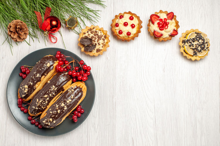 松树俯视图：灰色盘子上的巧克力馅饼和葡萄干 白色木桌上的松叶和圣诞玩具木头食物肉