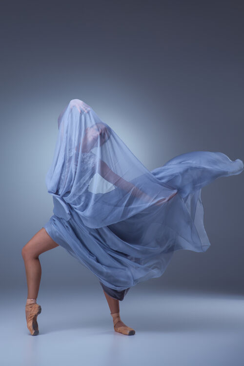 经典美丽的芭蕾舞演员在蓝色背景上穿着蓝色长裙跳舞姿势丝绸奢华