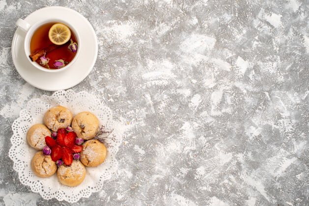 食物俯瞰美味的沙曲奇与草莓和一杯茶在白色的表面糖水果浆果