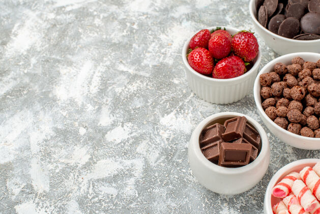 多汁在灰白色地面的右侧 上半部分是白色的 红色的糖果 草莓 巧克力 谷类食品和可可的碗浆果可食用水果草莓