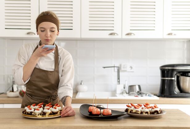 糕点中镜头的女人正在为甜点拍照烹饪厨师专业
