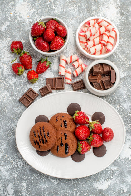 盘子白色椭圆形盘子上的饼干草莓和圆巧克力 灰白色桌子上的糖果草莓巧克力碗食品水果可食用水果