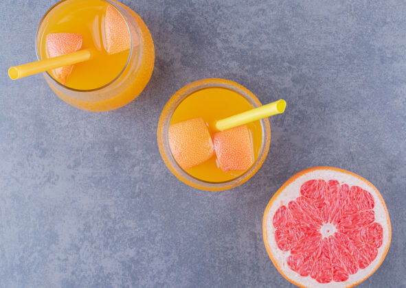 果汁灰色背景上新鲜橙汁和成熟葡萄柚的俯视图圆形玻璃杯新鲜