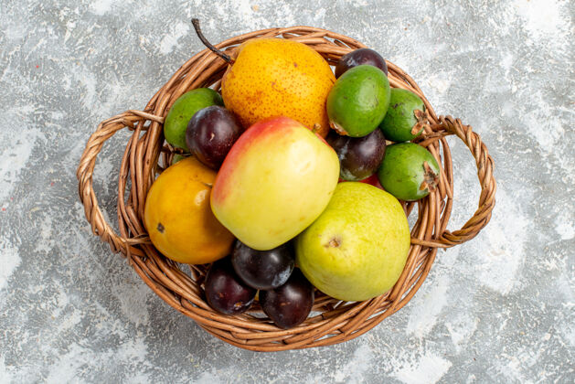 水果顶视图塑料柳条篮子 灰色的桌子上放着苹果 梨 李子和柿子饮食食品灰色