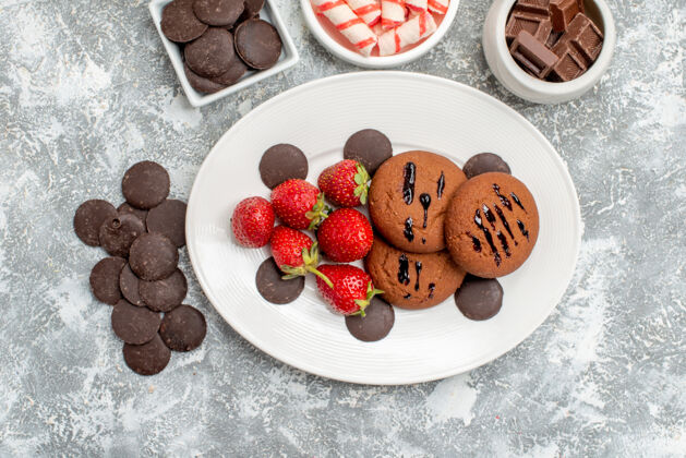 圆形俯瞰饼干草莓和圆形巧克力放在椭圆形的盘子里 糖果巧克力和圆形苦巧克力放在灰白色的桌子上蓝莓巧克力草莓