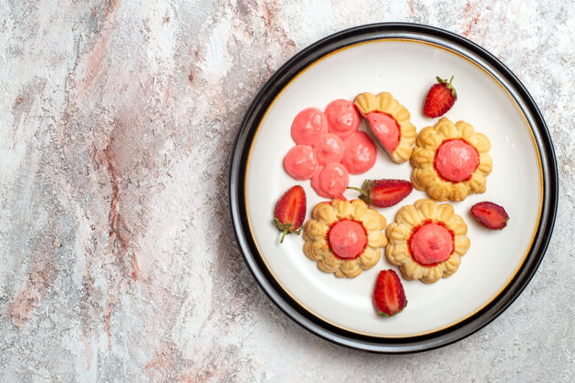 蔬菜白色表面上有草莓果冻的美味甜饼俯视图新鲜浆果盘子