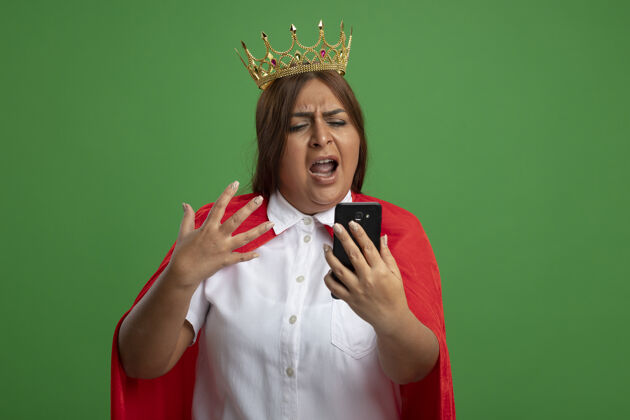 绿色愤怒的中年女超人戴着王冠 手持手机看着绿色的隔离皇冠穿中年