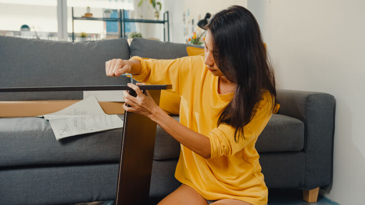 家具快乐的亚洲年轻女子打开箱子 阅读组装新家具的说明亚洲人服务说明