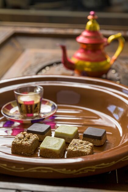 方形特写镜头不同类型的方形糖果与茶在一个木制托盘叉子餐厅桌子